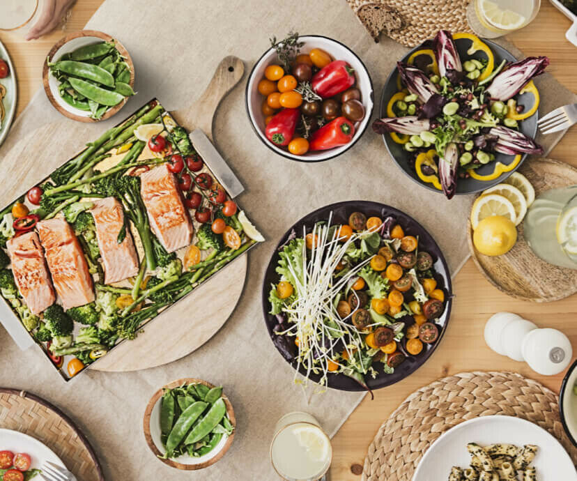 Salmon and roasted vegetables on a sheet pan with side salads and drinks.