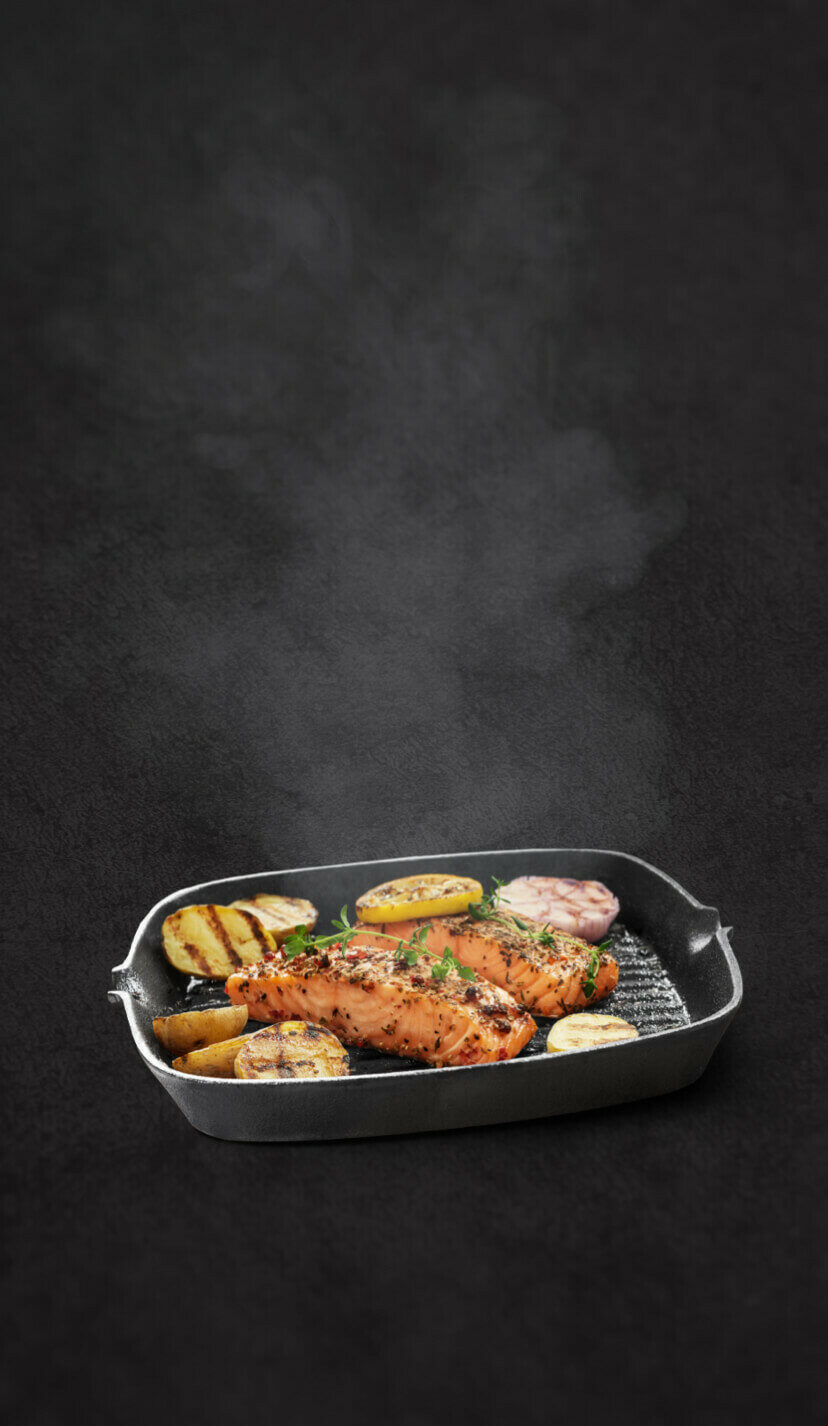 Grilled salmon with potatoes and lemon in a cast-iron skillet.