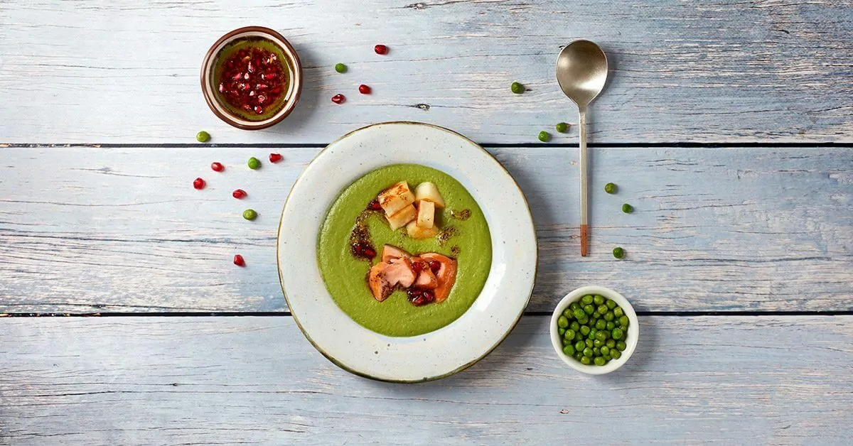 Green pea soup with salmon, diced potato, and pomegranate seeds.