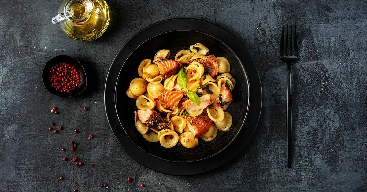 Orecchiette pasta with salmon, herbs, and pink peppercorns.